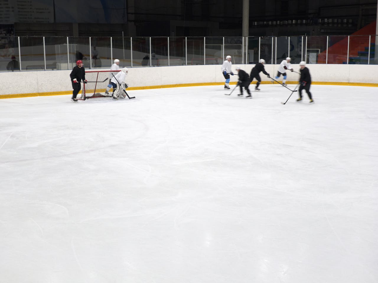 Dynamic hockey match indoors with players skating and maneuvering on an ice rink.