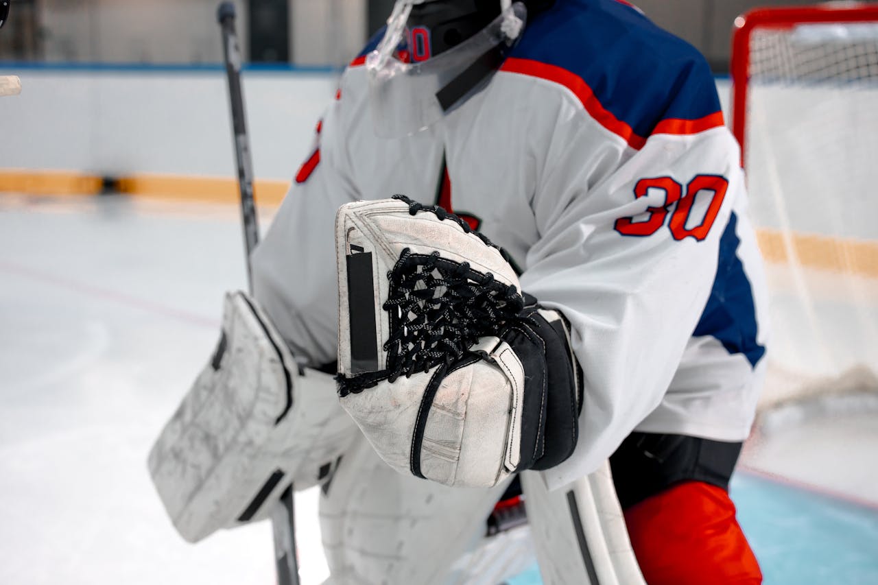Close-up of ice hockey goalie in protective gear during a match, ready to play.